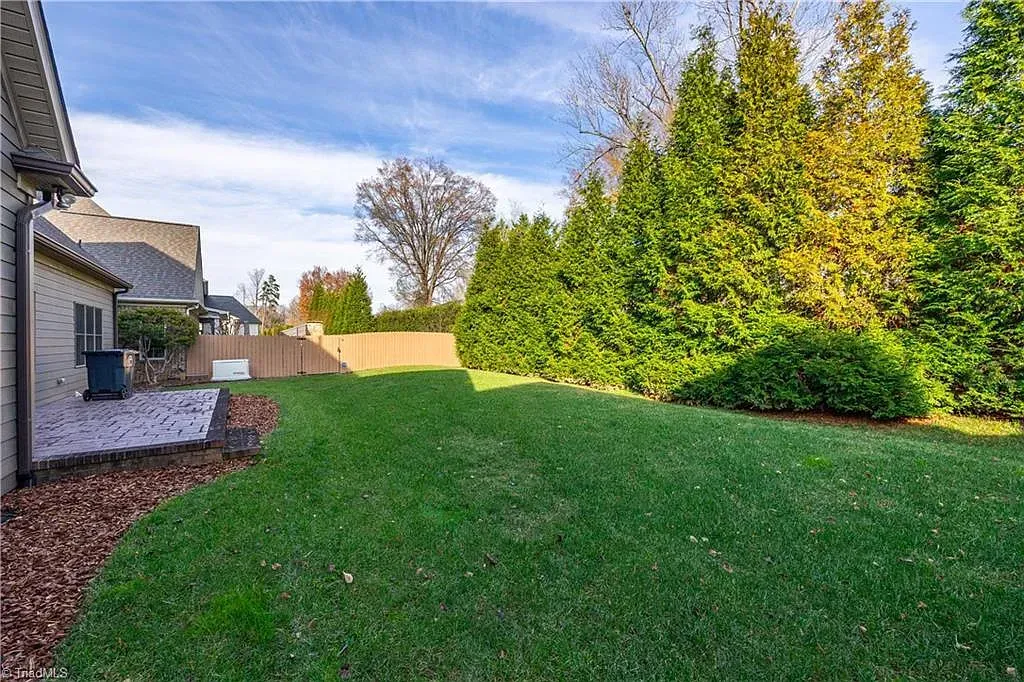 The backyard of a house with a lush green lawn and trees.