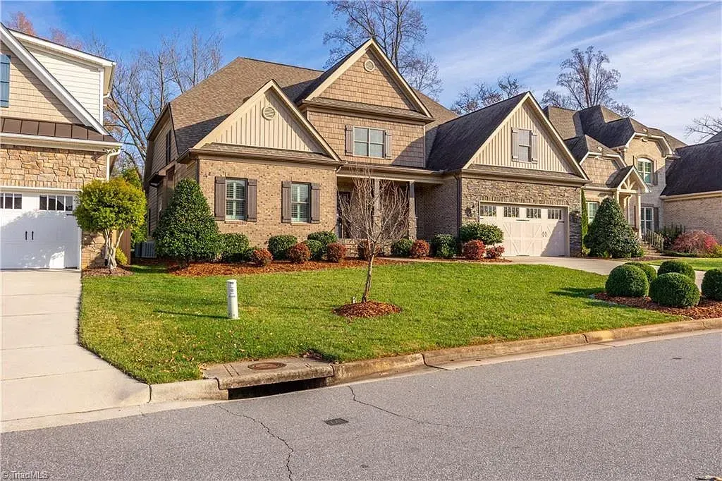 A large brick house with a large lawn in front of it.