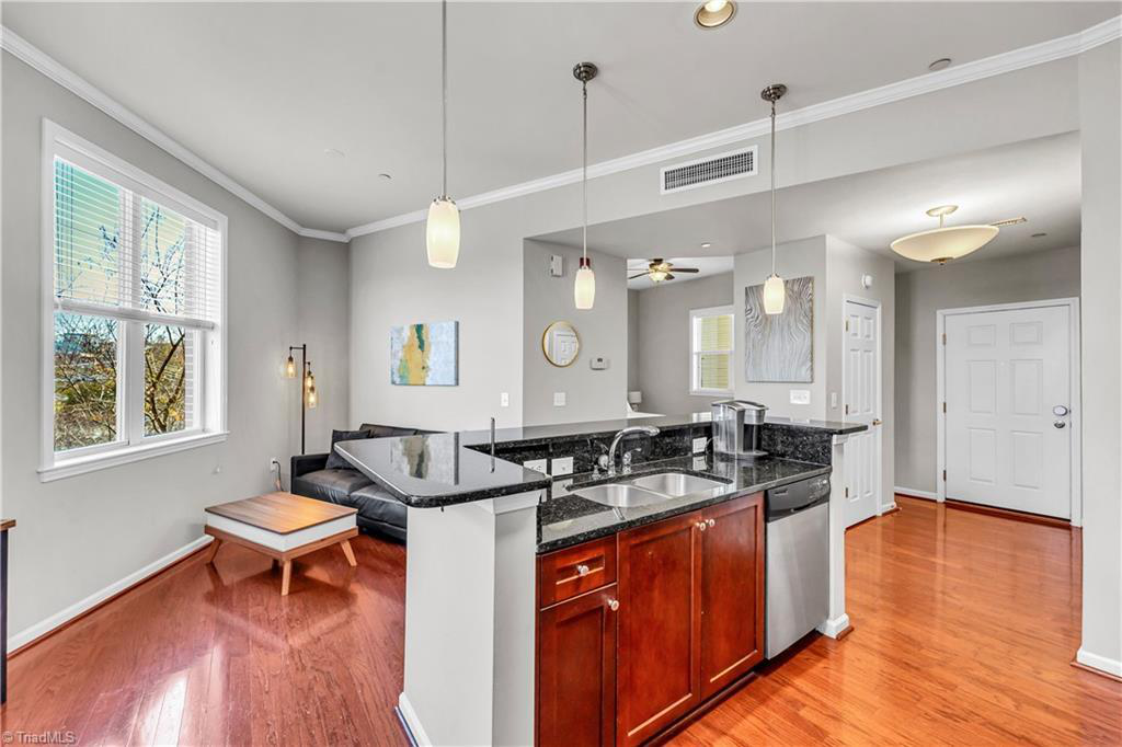 A kitchen and living room in a house with hardwood floors and stainless steel appliances.
