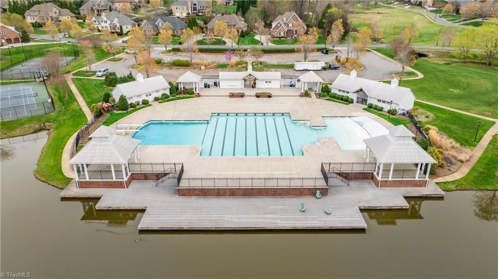 Aerial view of a large outdoor pool complex beside a river, with white buildings and green lawns.