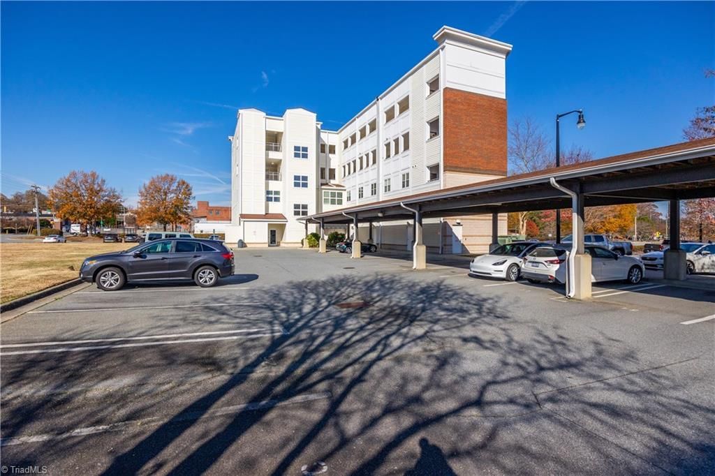 A parking lot with cars parked in front of a large building.