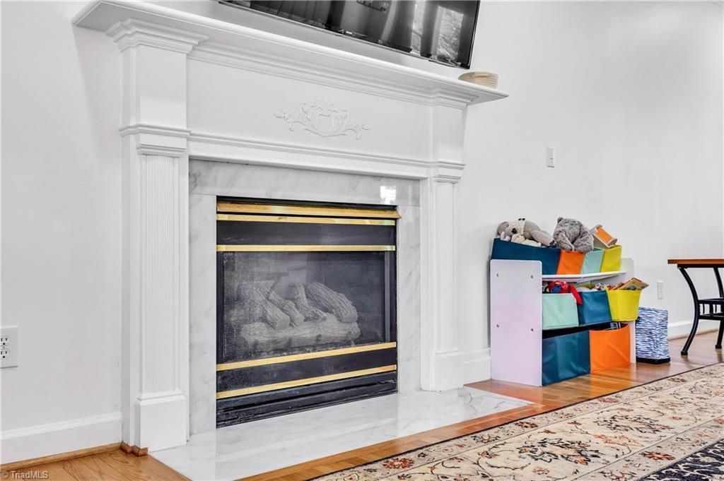 White fireplace with ornate mantel beside colorful gift bags in a bright room
