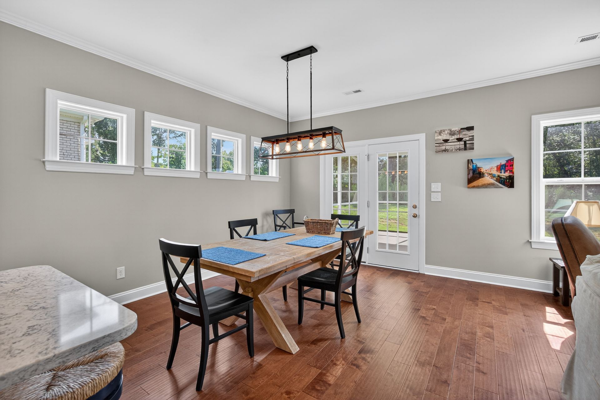 Dining room with wooden table, black chairs, and large windows in a bright gray interior