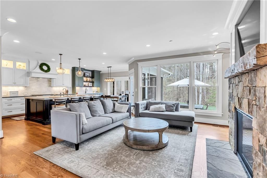 Bright open living room with gray sofa, fireplace, round coffee table, and large windows overlooking snow.