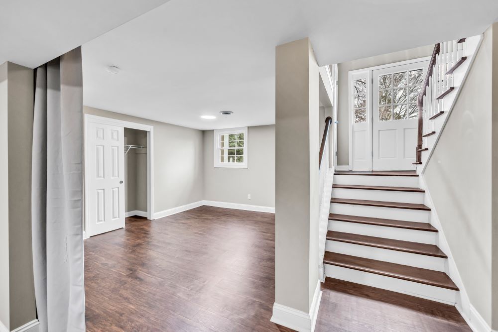 Empty entryway with hardwood floors, staircase, and front door in a bright home interior