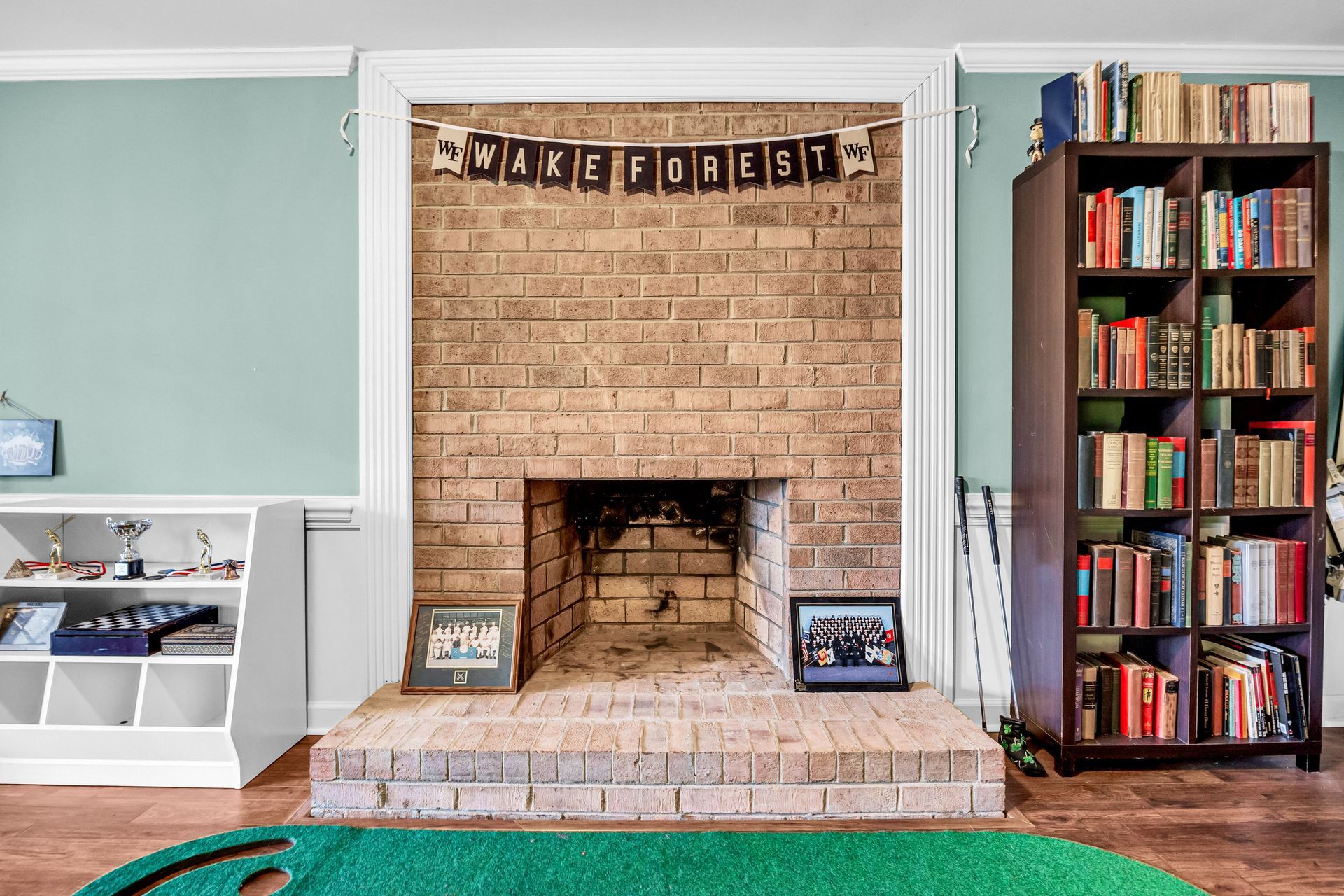 Living room with brick fireplace, bunting, and a tall bookshelf beside it