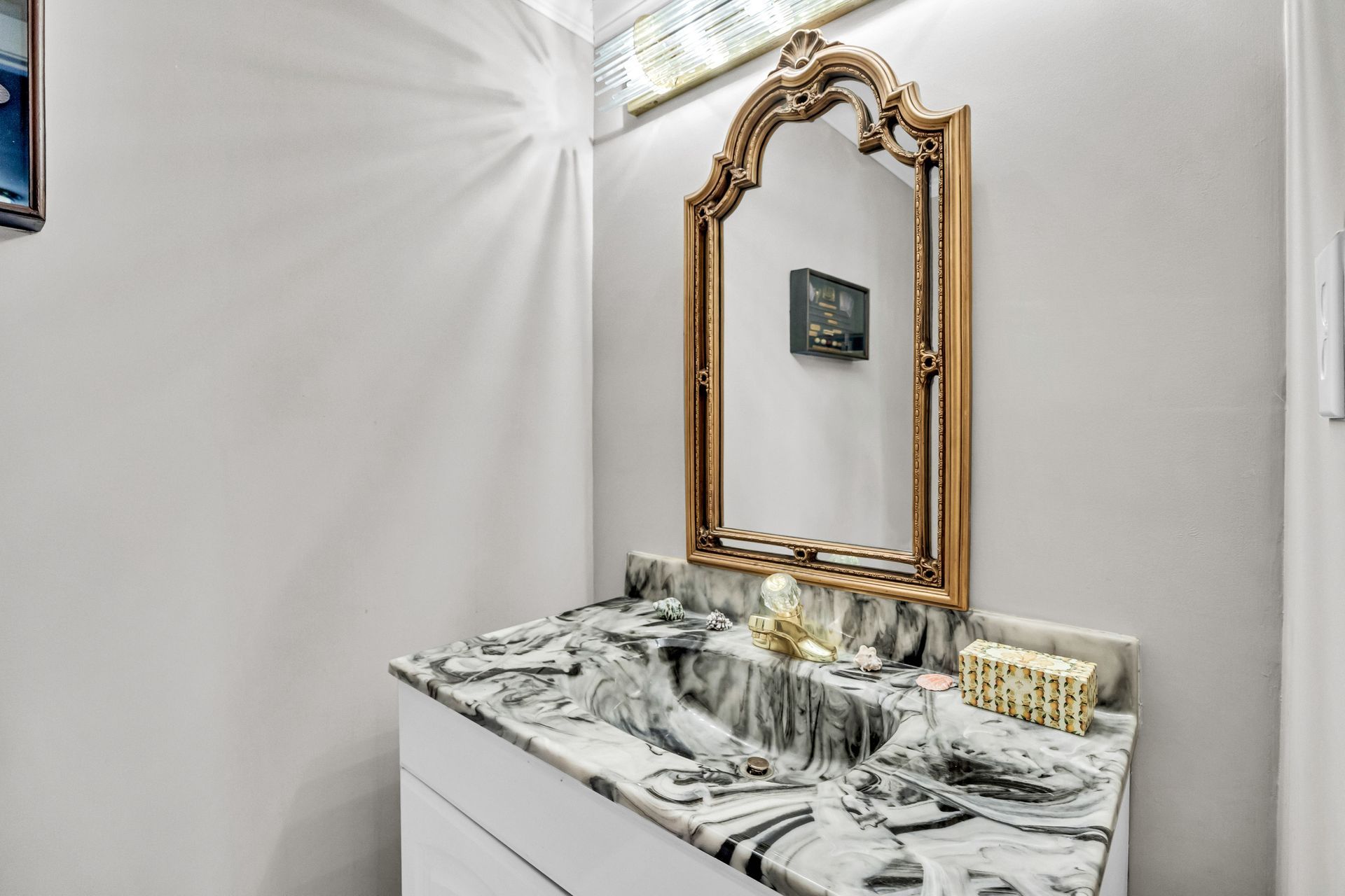 Elegant vanity with gold-framed mirror and marble countertop in a bright room