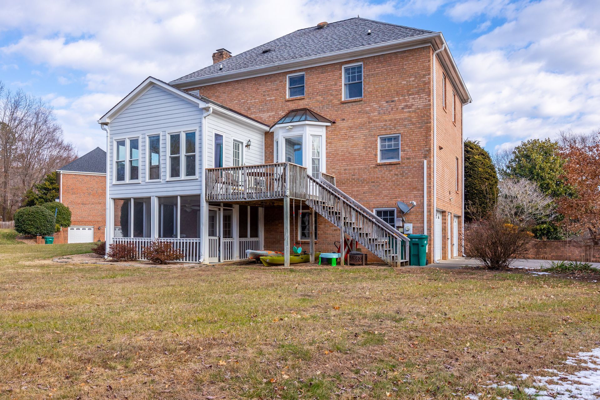 Two-story brick house with white porch and exterior staircase on a grassy yard