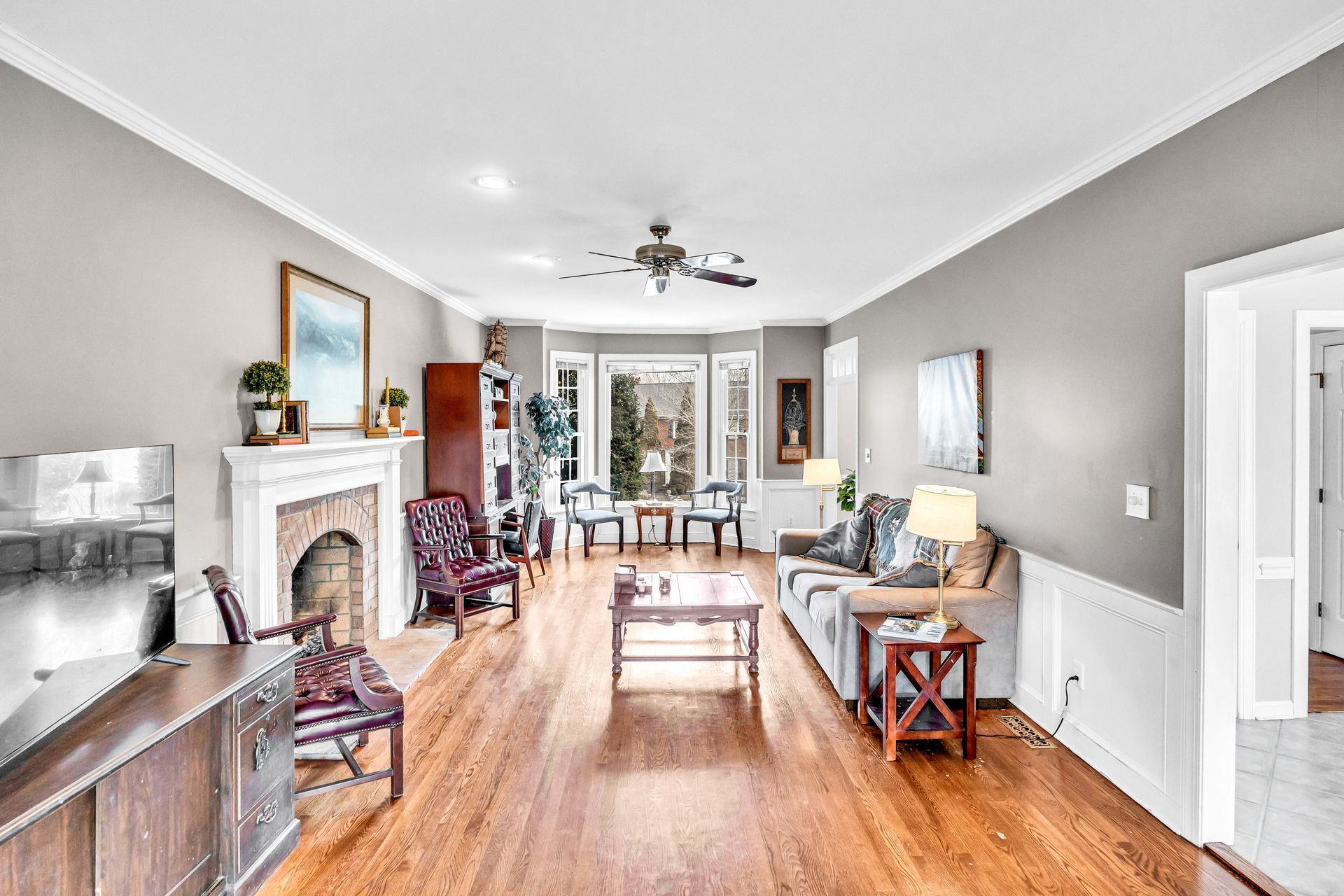 Bright living room with hardwood floors, fireplace, gray walls, and seating facing French doors.