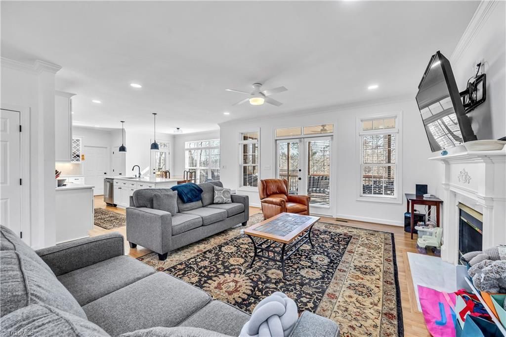 Bright living room with gray sofas, patterned rug, fireplace, and French doors opening to a patio