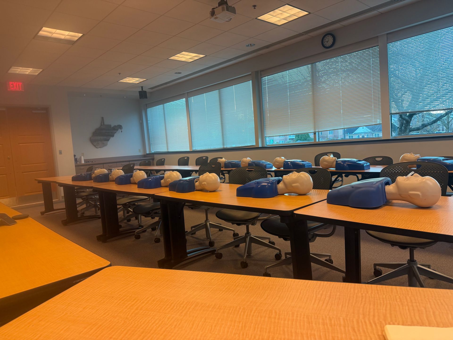 Classroom with CPR training dummies on tables; window blinds are up.