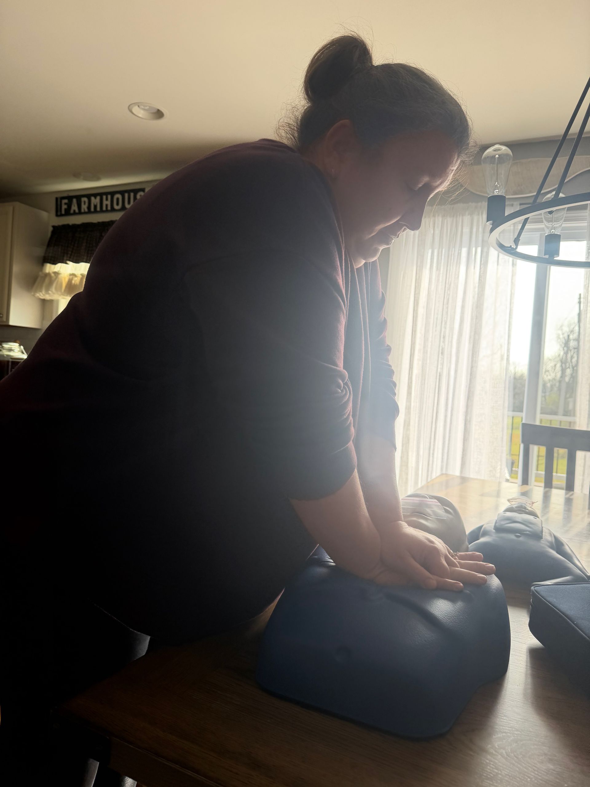 Person practicing CPR on a training dummy, indoors.