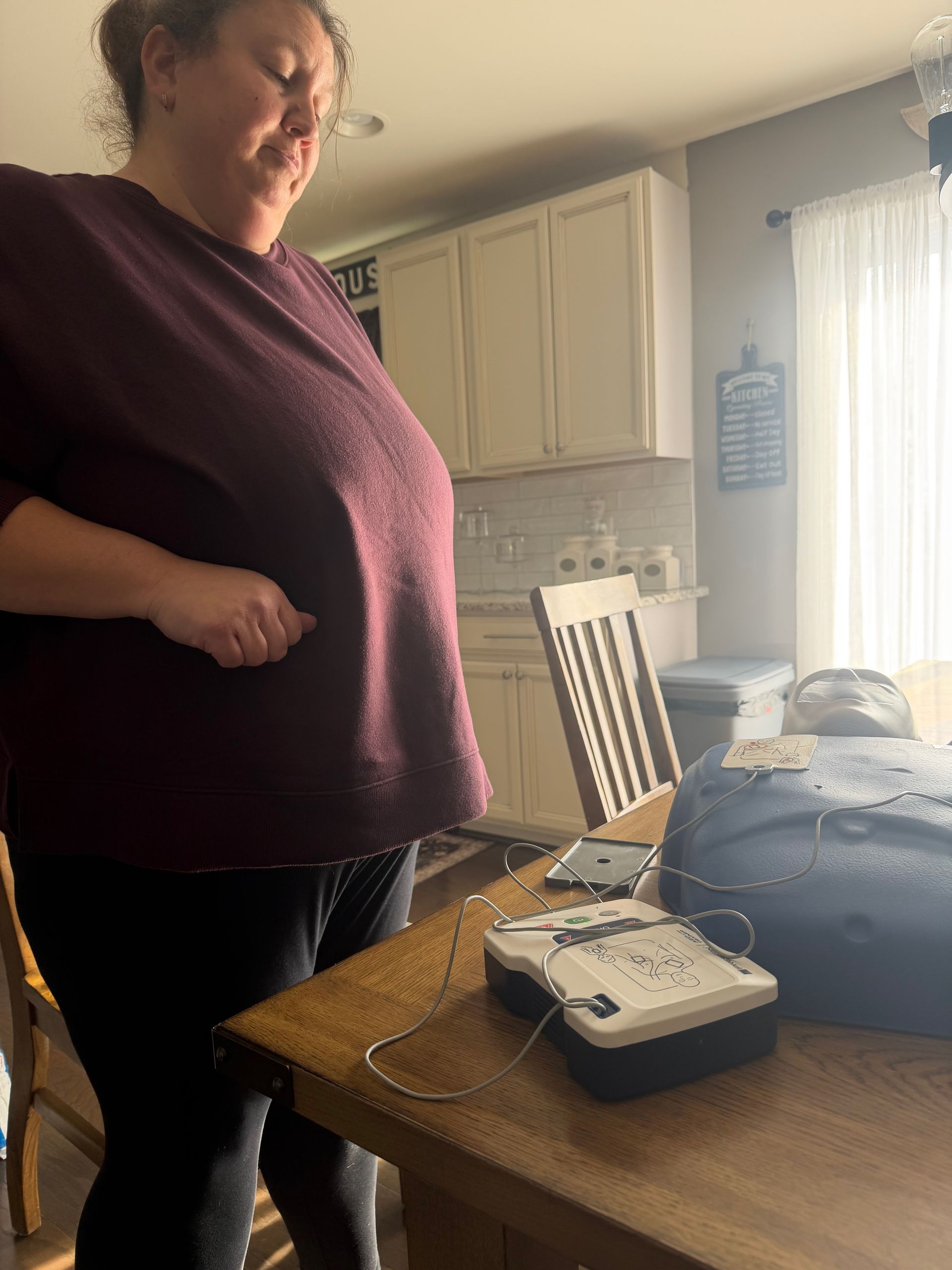 Woman by a table with medical equipment; kitchen setting.