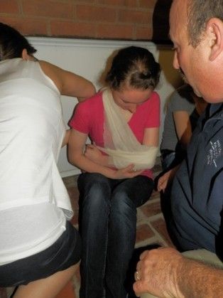 Woman with arm in sling, surrounded by people, possibly injured.