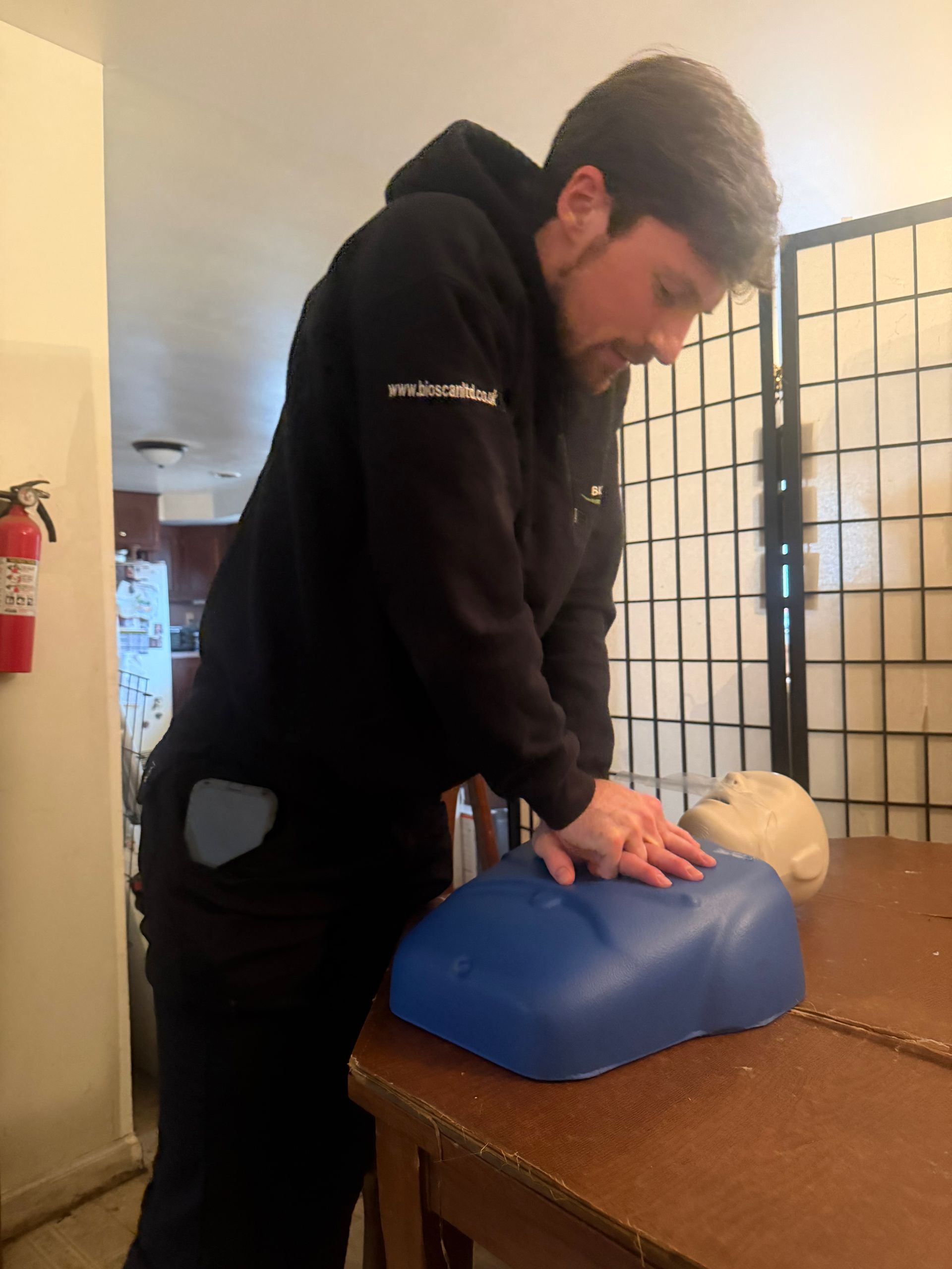 Man practicing CPR on a training dummy, indoors.