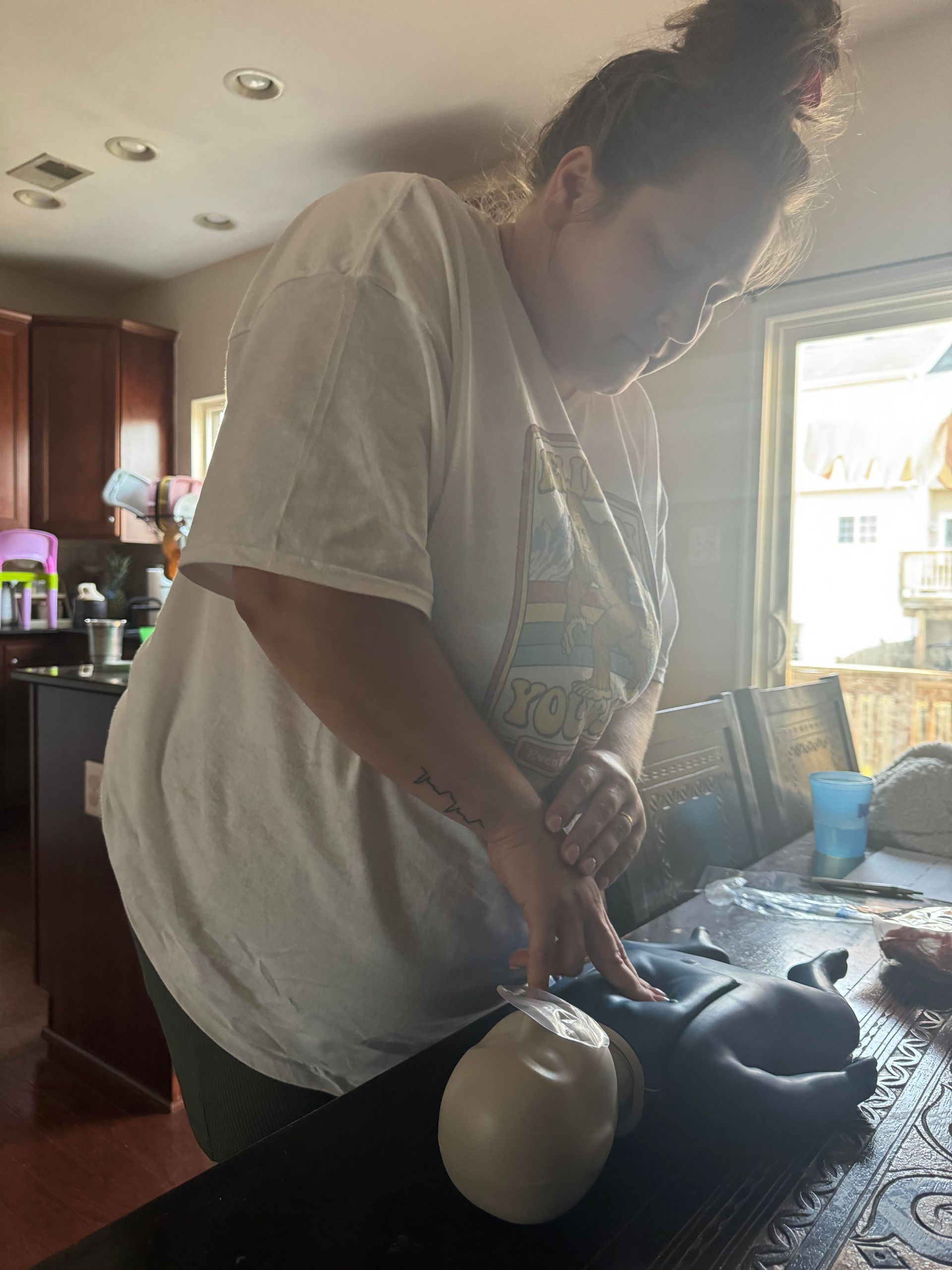 Woman in white shirt cutting food on a black surface in a kitchen.