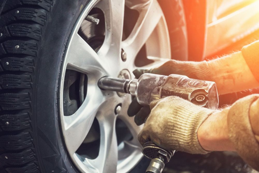 Un meccanico utilizza una chiave a percussione per rimuovere un dado da una ruota di un'auto.