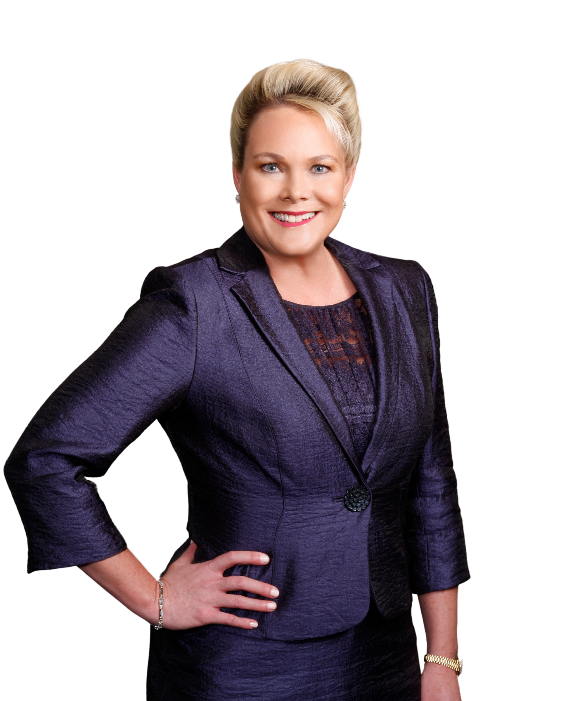 Woman in a dark blue suit, smiling with her hand on her hip.