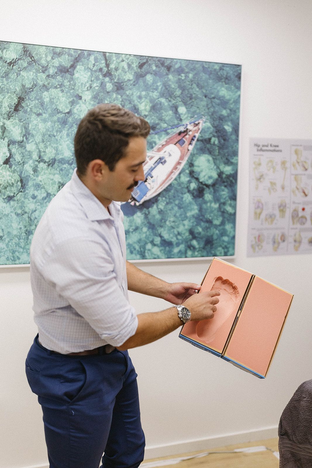 a man is pointing to an imprint of a foot on a red surface — Biomedical Sports Podiatry in Diamond Beach, NSW