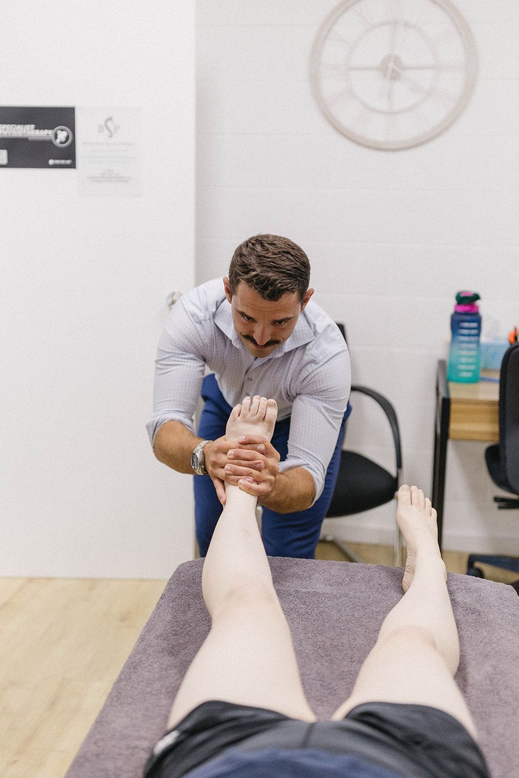 Physical Therapist Examining a Patient's Foot and Ankle in An Office — Biomedical Sports Podiatry in Forster, NSW