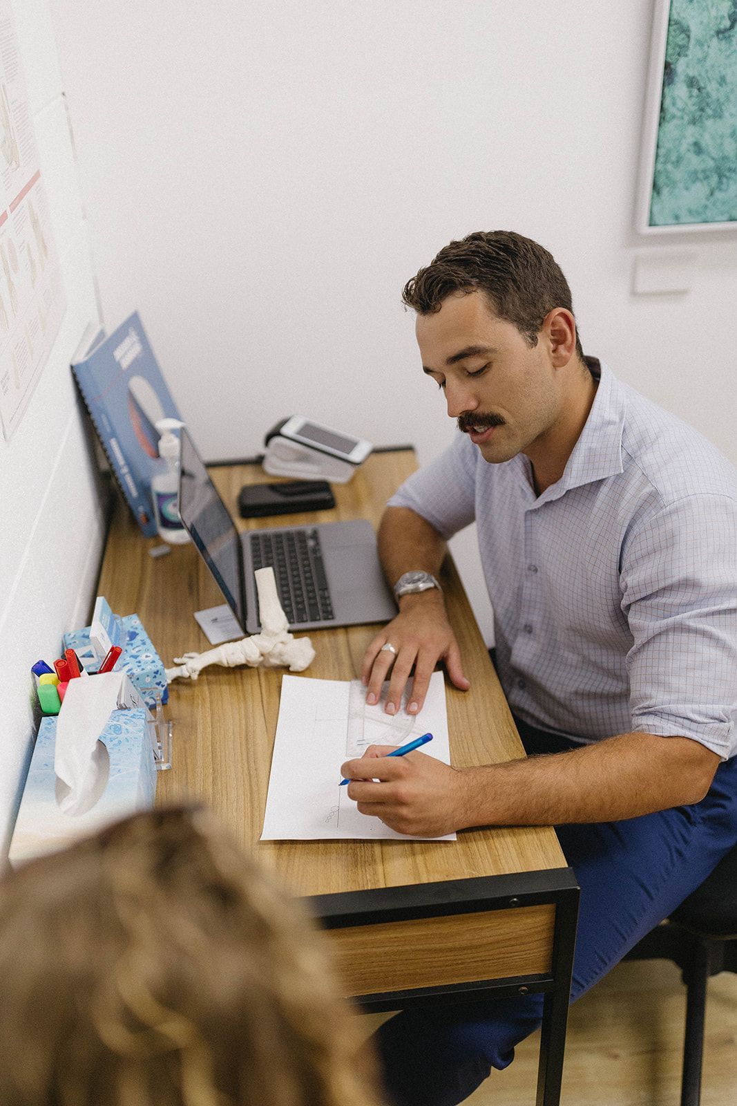 Man With Moustache Writing at a Desk— Biomedical Sports Podiatry in Forster, NSW