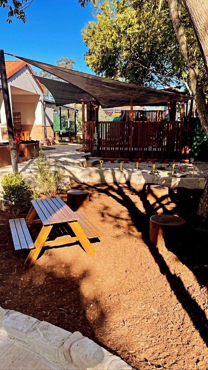 a picnic table is sitting in the middle of a dirt yard . Childcare, Montessori, Gold Coast, Warwick, Jindabyne.
