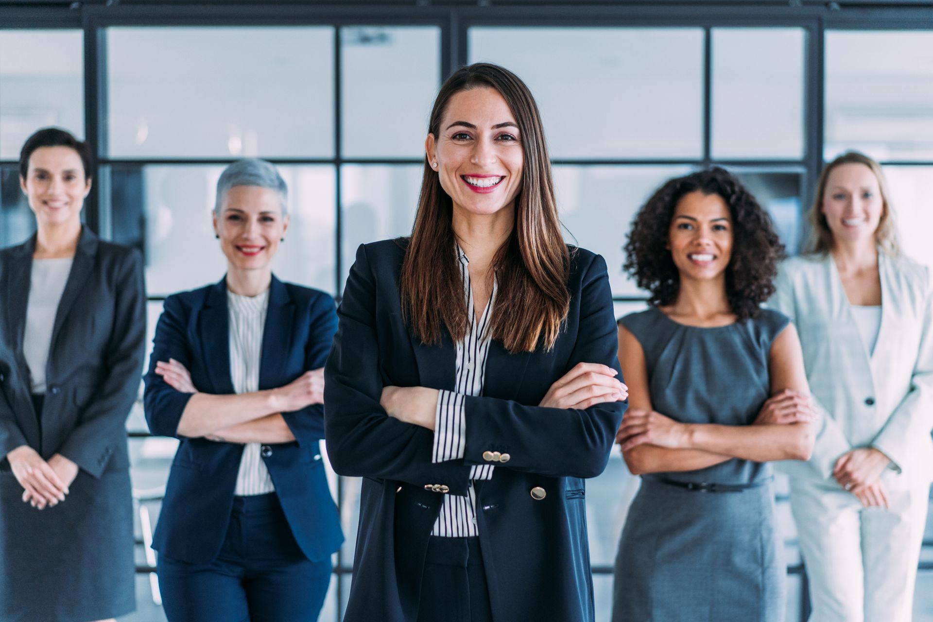 A group of business women standing next to each other with their arms crossed.