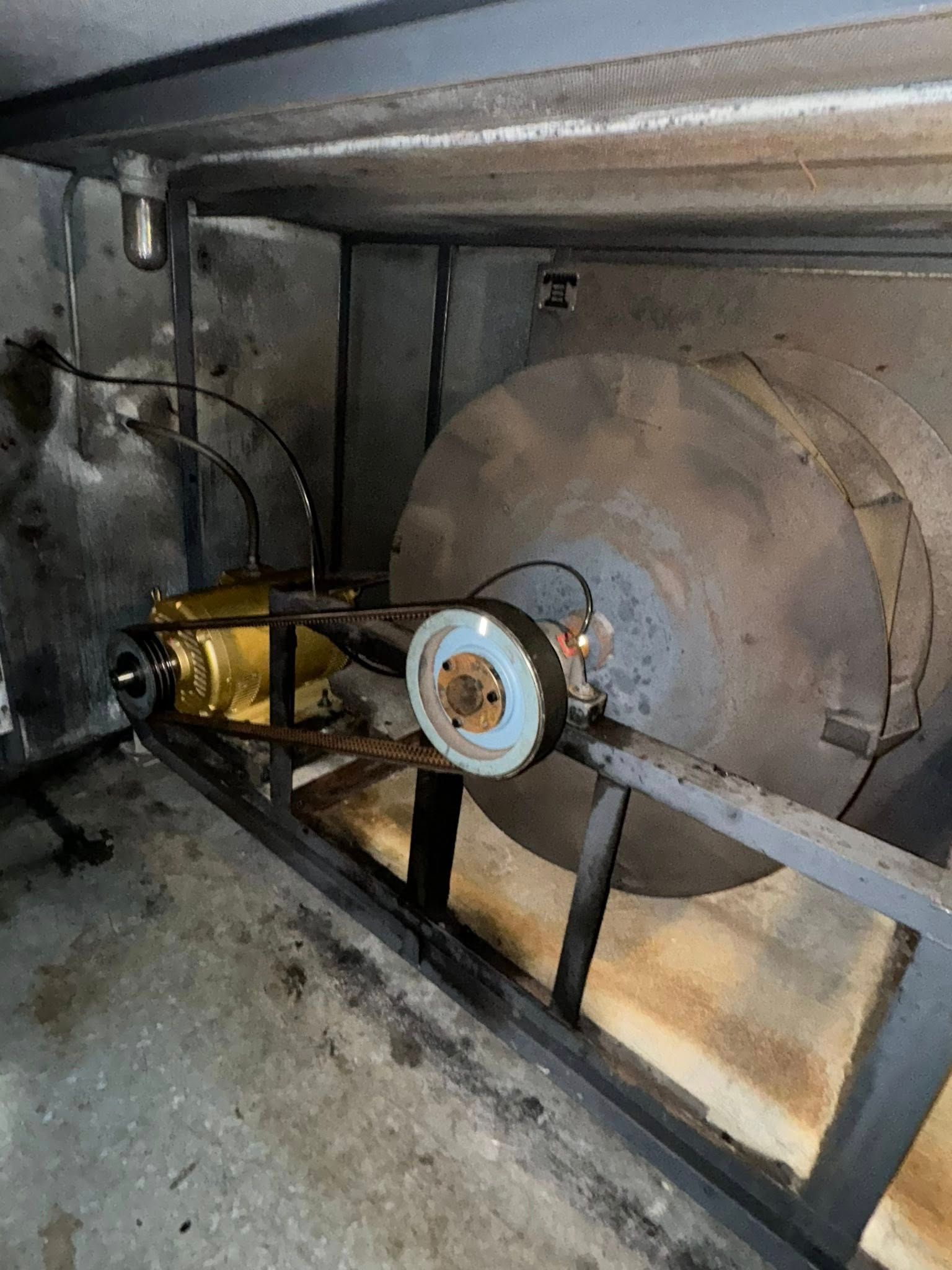 Industrial machinery with a large cylindrical tank, pipes, and a motor in a concrete room