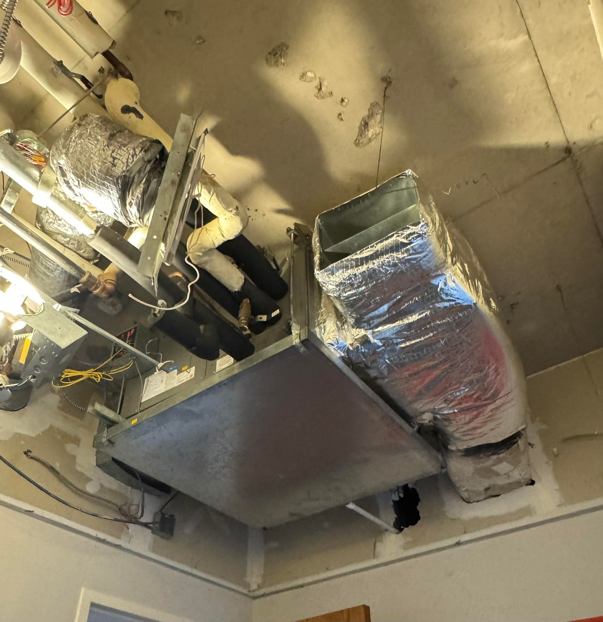 Ceiling HVAC ductwork and insulated pipes in an industrial room