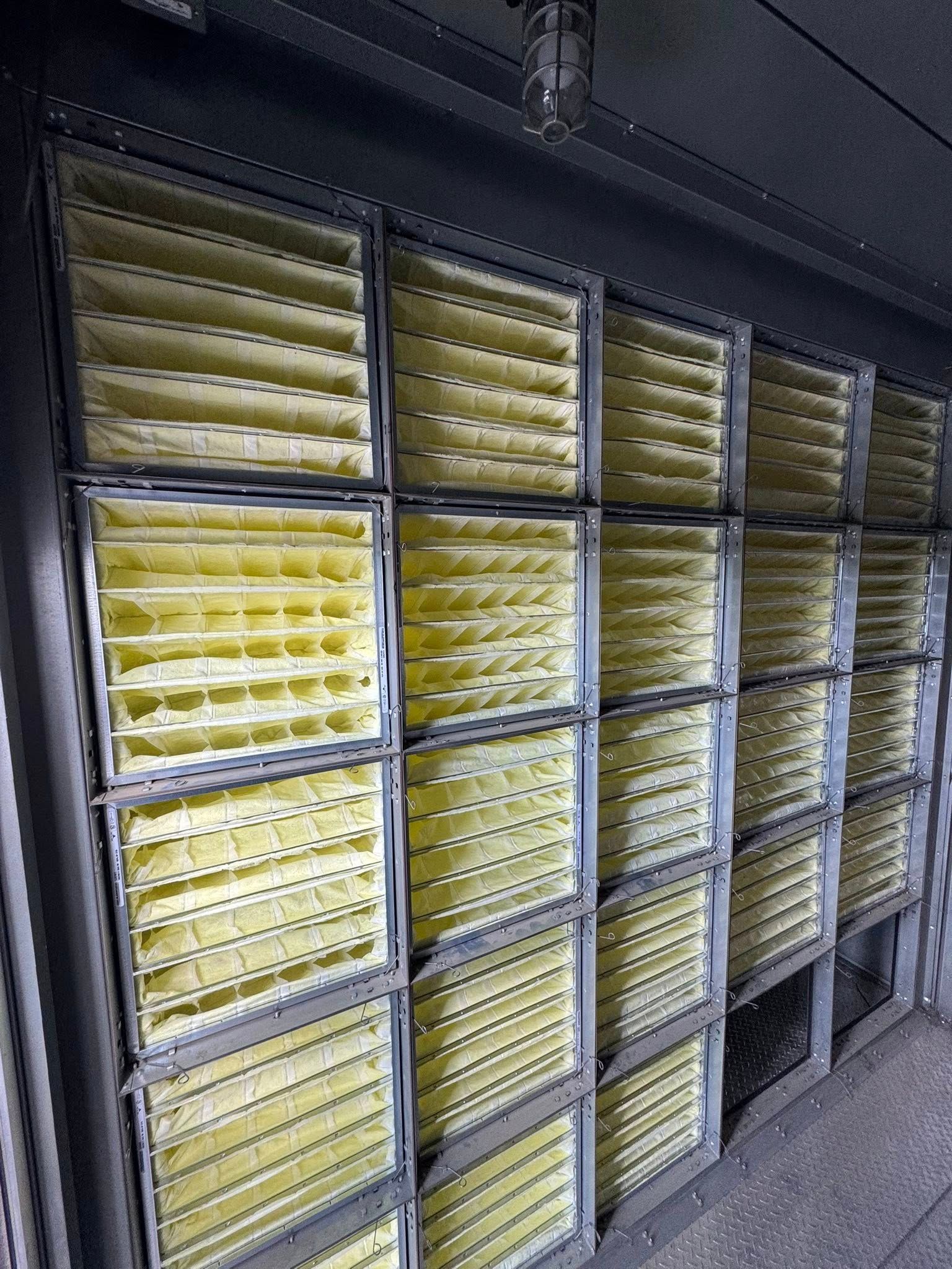 Rows of stacked yellow trays in a storage rack inside a dim industrial room