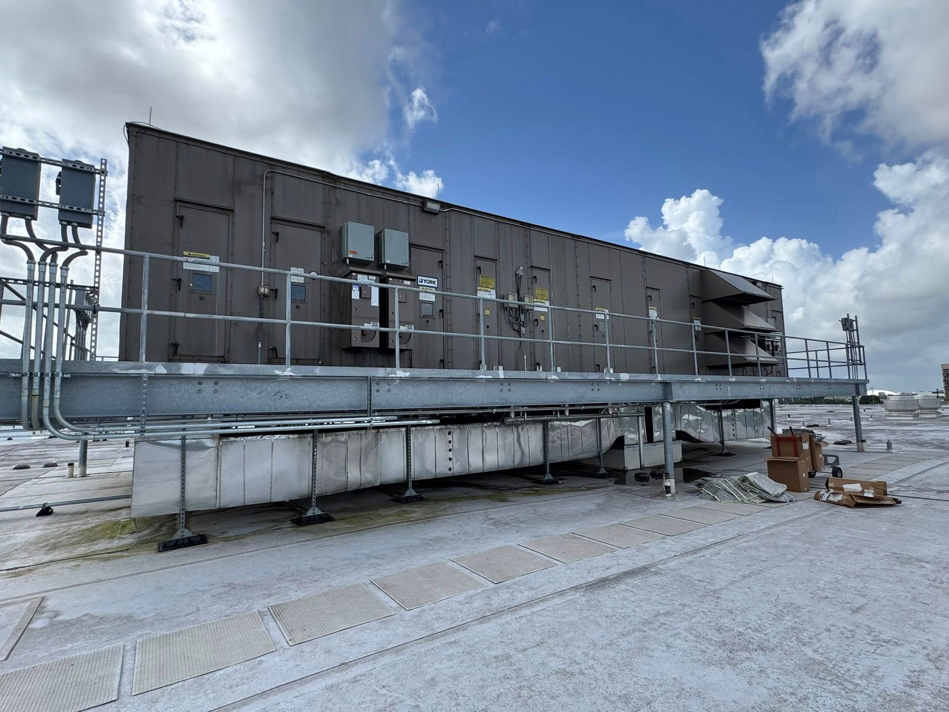 Rooftop construction site with scaffolding, gray walls, and blue sky with clouds
