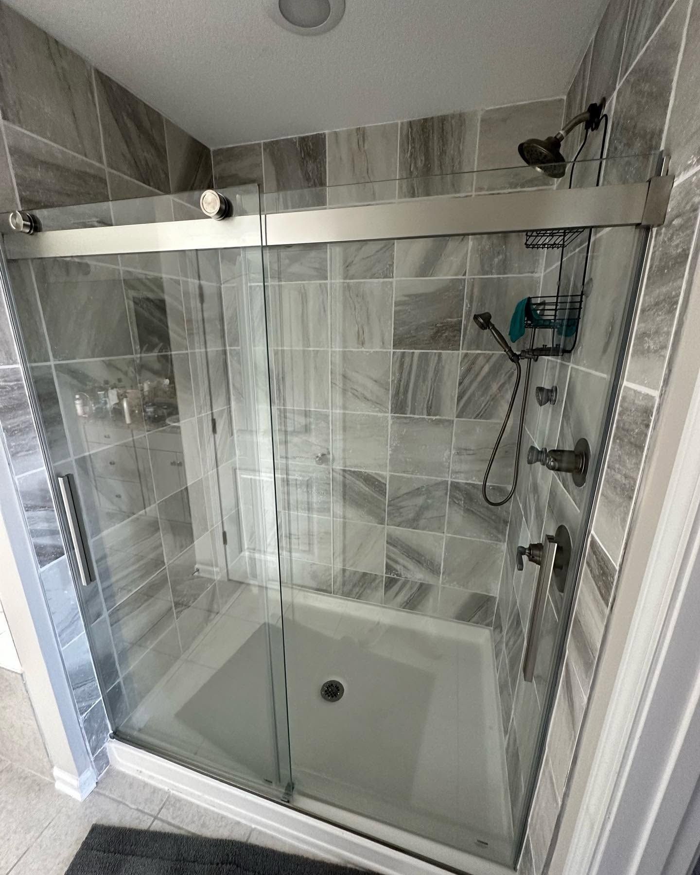 Modern bathroom with a glass-enclosed shower, tiled walls, and a handheld showerhead