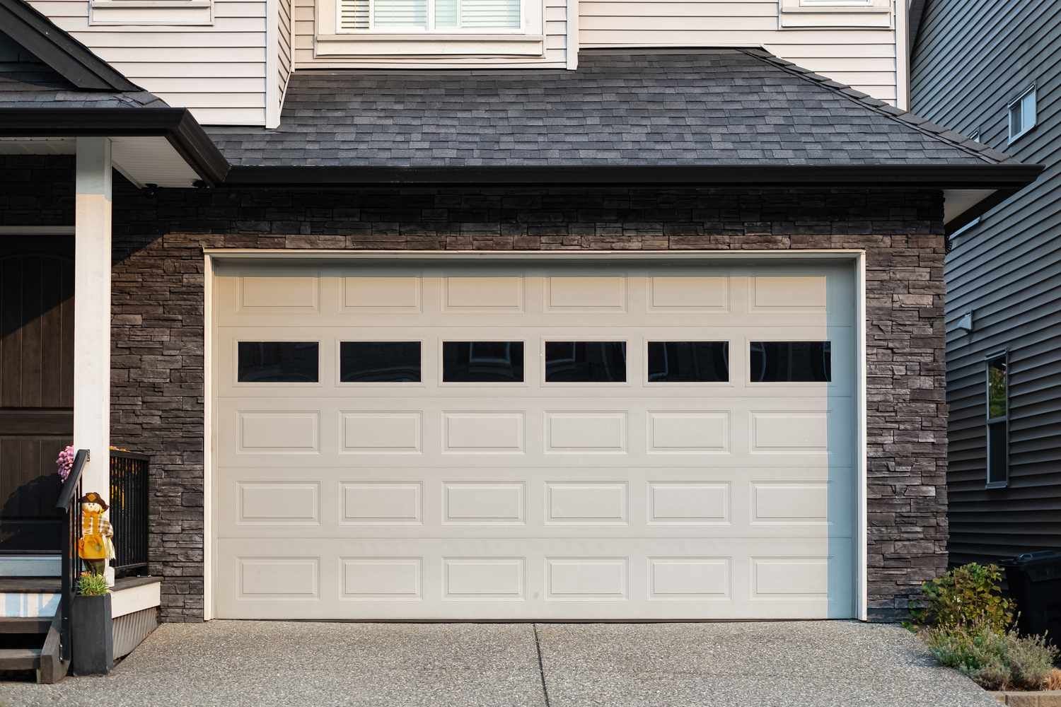 Suburban house front with white garage door and brick facade