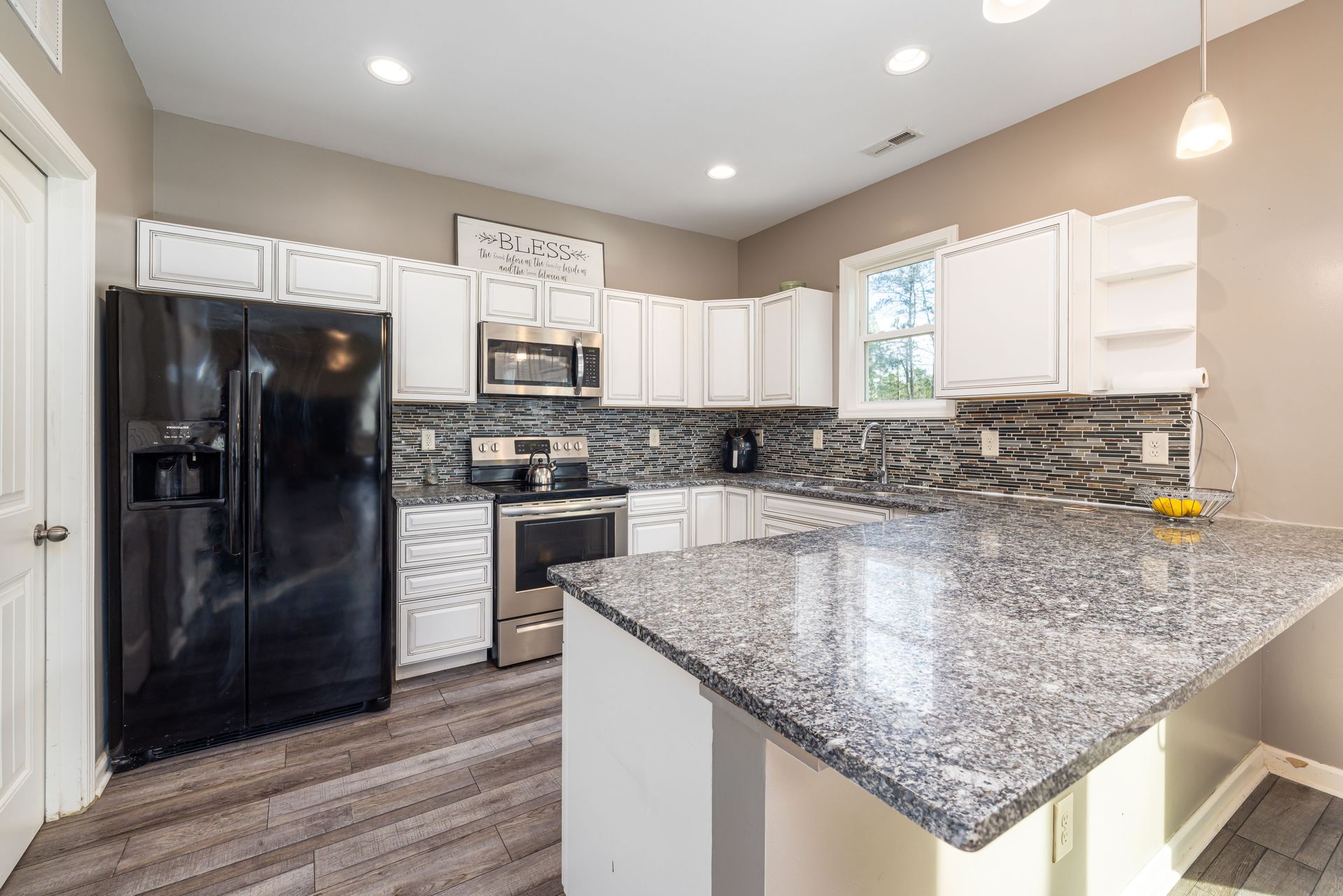 Bright modern kitchen with black appliances, white cabinets, and granite countertops