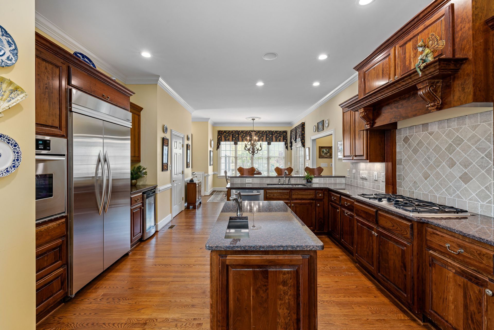 Modern kitchen with stainless steel appliances, dark wood cabinets, island, and tiled backsplash
