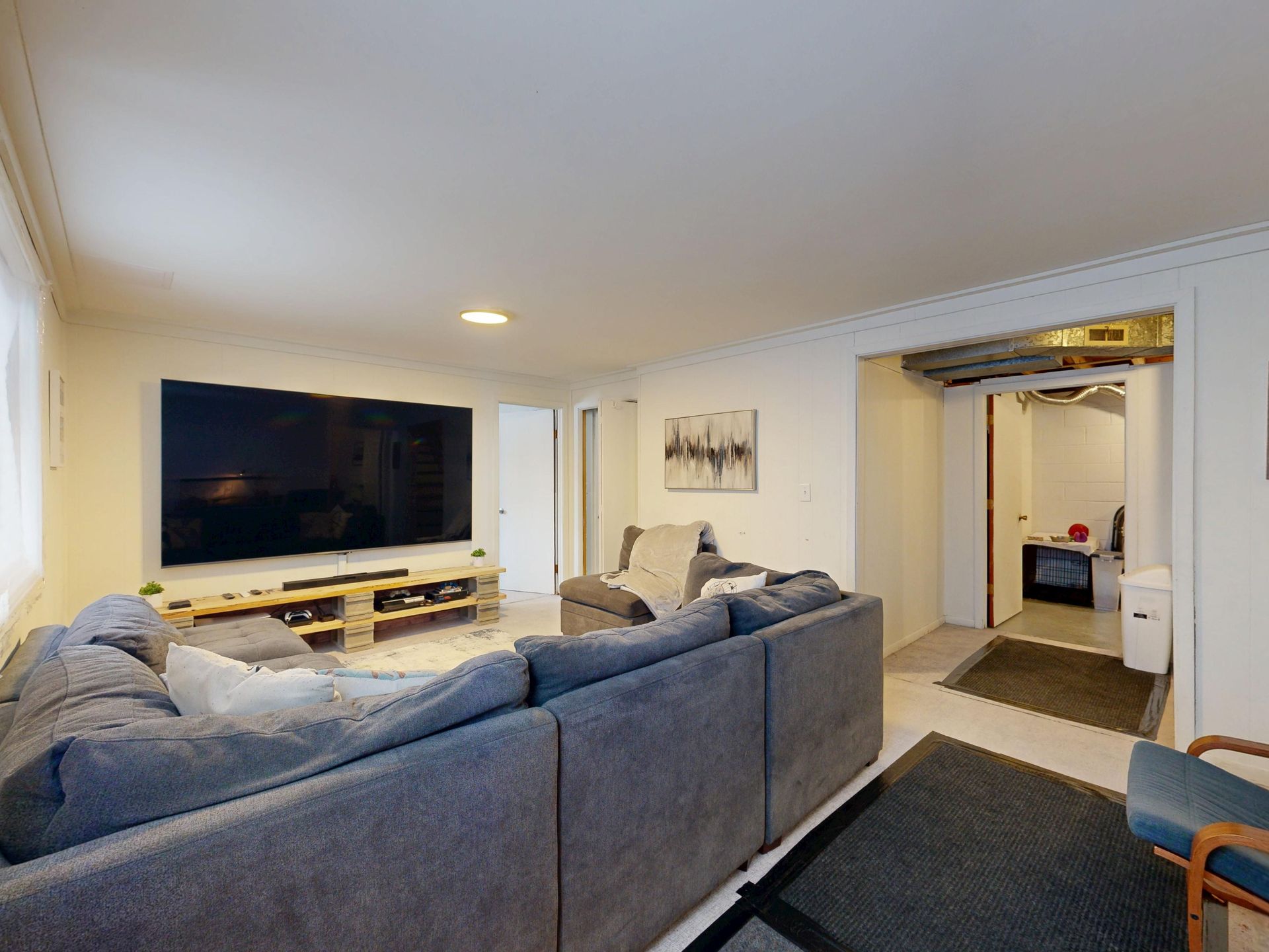 Modern living room with gray sectional sofa, large TV, and open doorway to a hallway