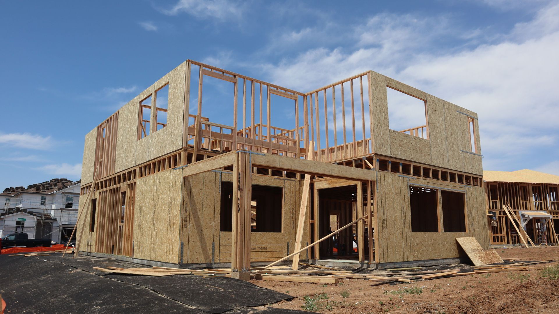 Partially framed two-story house under construction on a sunny day