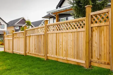 Wooden privacy fence with lattice top along a green lawn in a suburban neighborhood