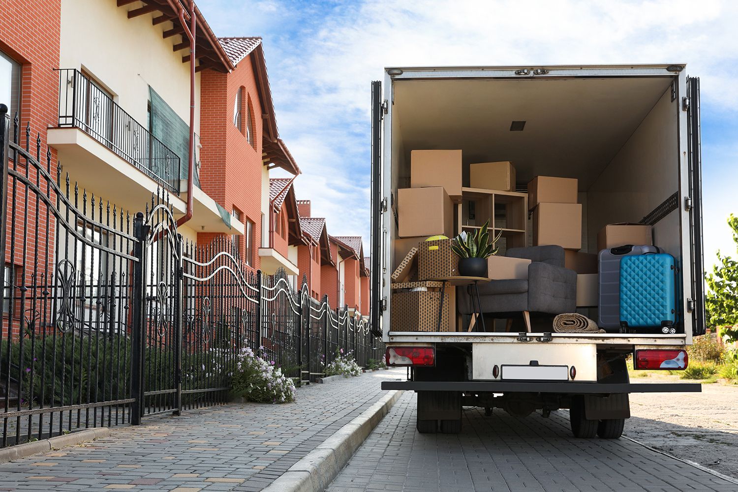 A van full of moving boxes and furniture parked outside near a row of houses.