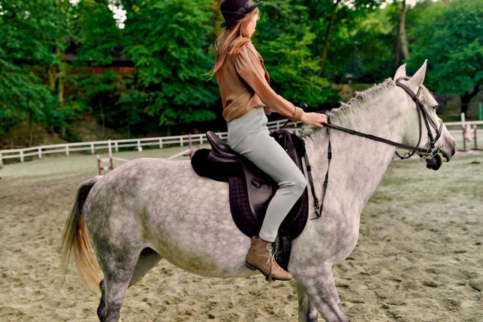 Riding dapple grey horse at hippodrome by female jockey