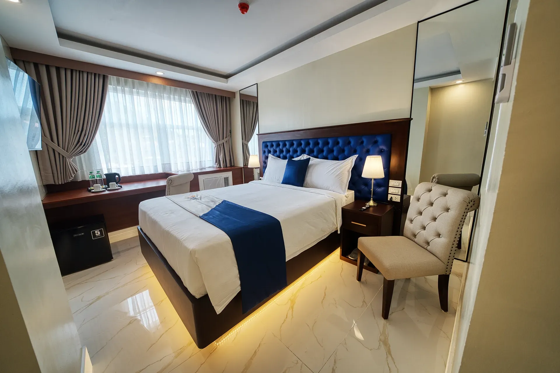 A hotel room with a king size bed and a chair.