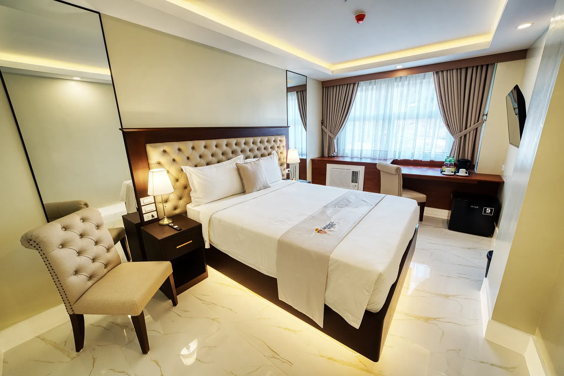 A hotel room with a large bed and a chair
