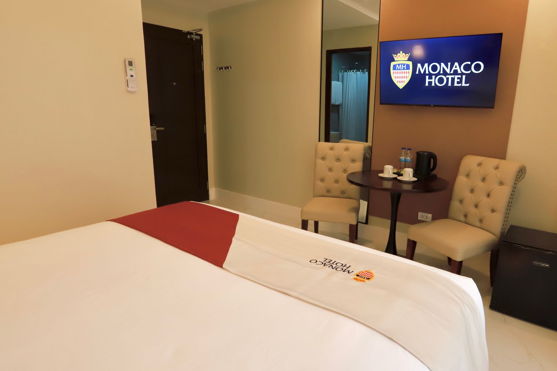 A hotel room with a bed , chairs , table and television.