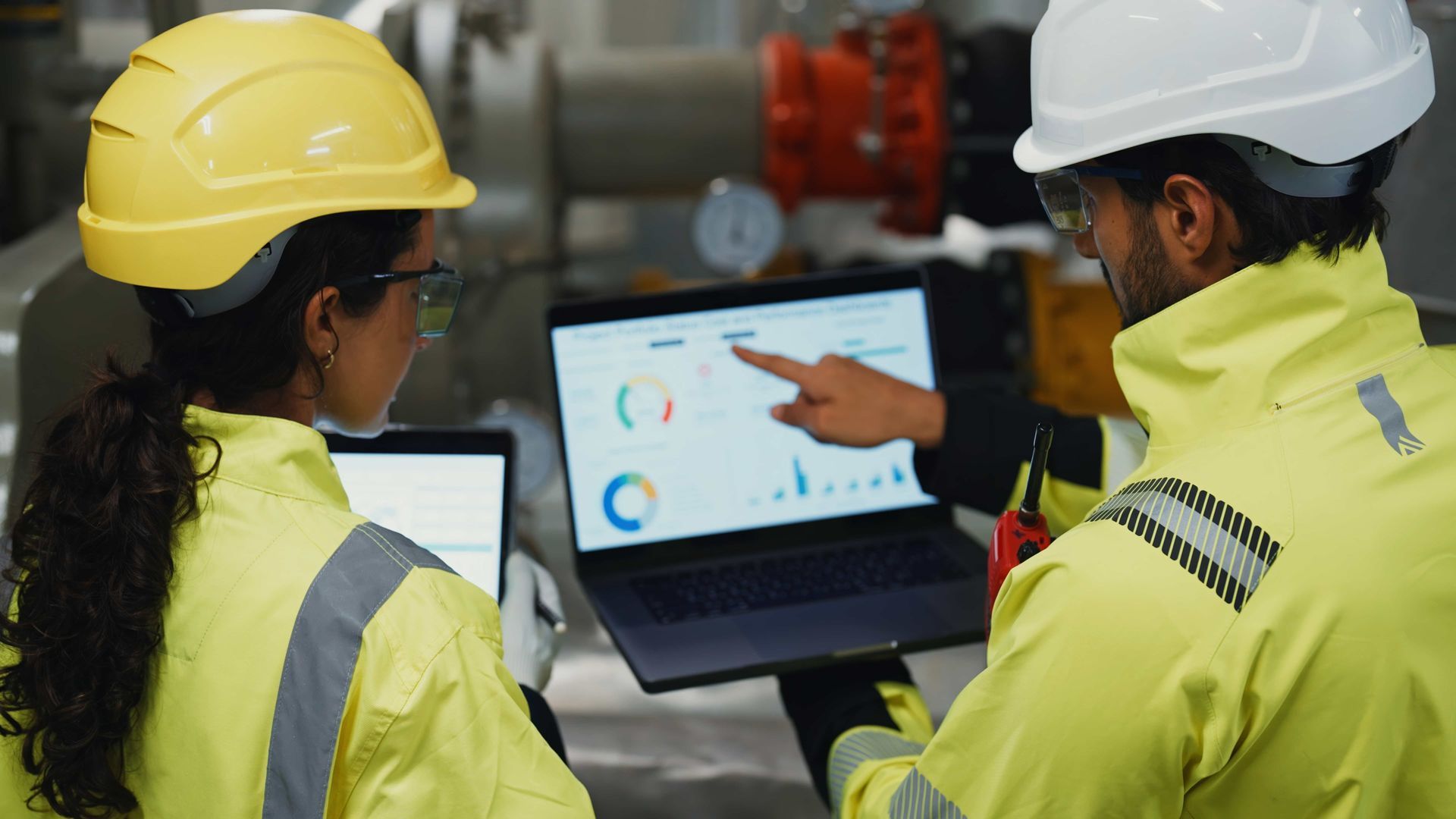 Technicians reviewing building automation systems data in a mechanical room.