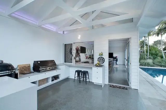 A Kitchen With a Grill and Stools Next to a Pool — Michael Duncan Constructions Pty Ltd in Robina, QLD