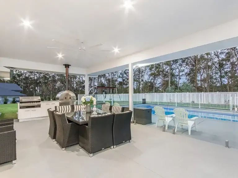 A Patio With a Table and Chairs and a Swimming Pool — Michael Duncan Constructions Pty Ltd in Burleigh Heads, QLD