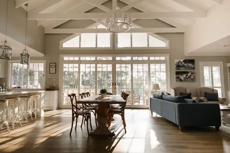 A Living Room With a Dining Table and Sliding Glass Doors — Michael Duncan Constructions Pty Ltd in Robina, QLD