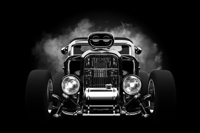 A black and white photo of a hot rod with smoke coming out of it.