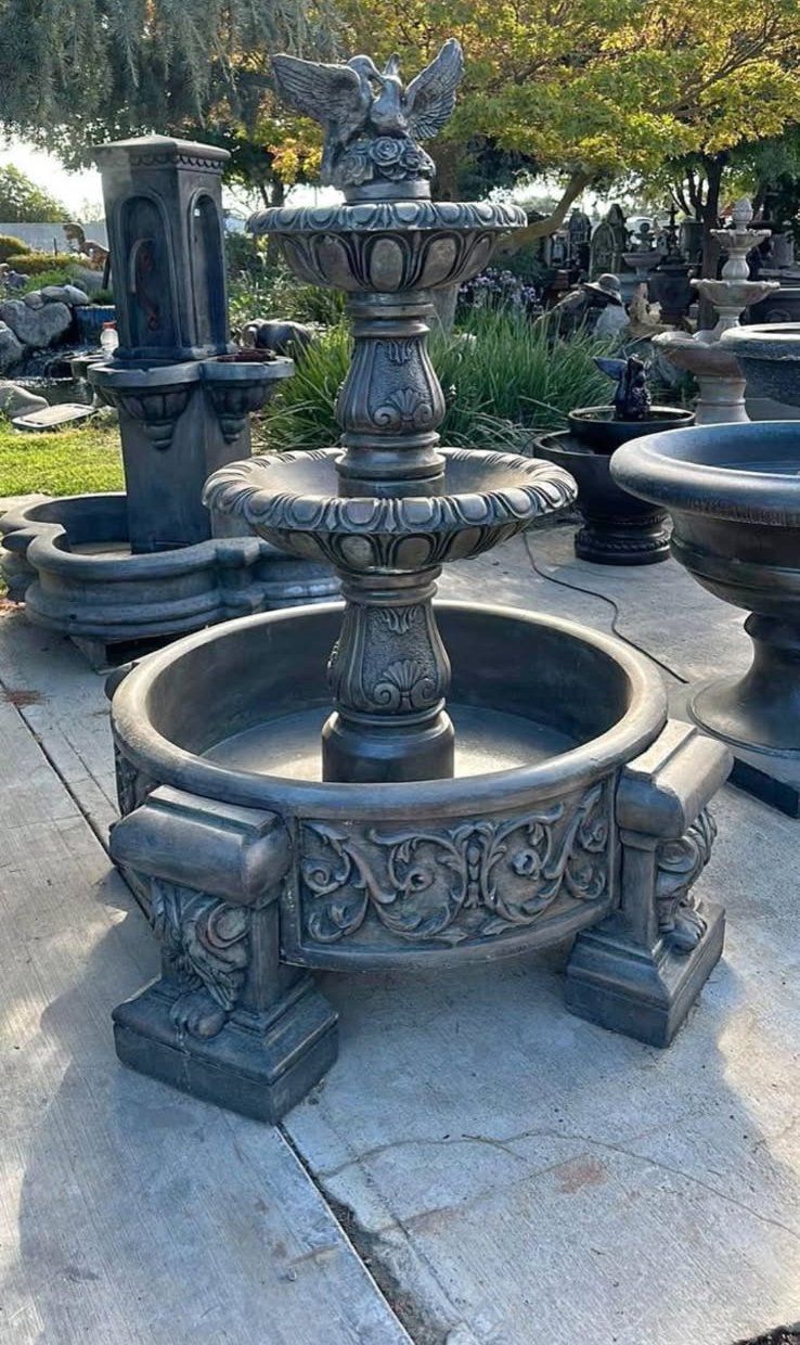 Ornate stone fountain in a garden courtyard, with a circular basin and carved pedestal.