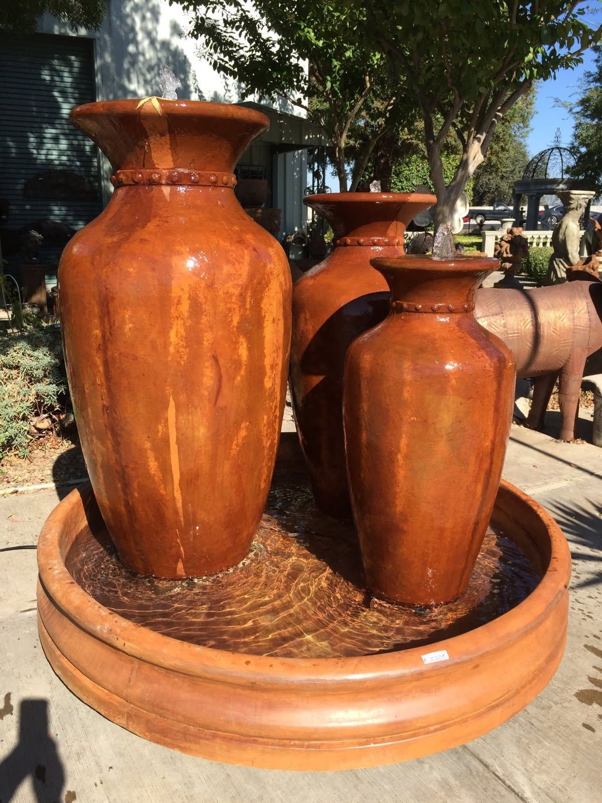 Three large terracotta urns in a round fountain, outdoors in sunlight